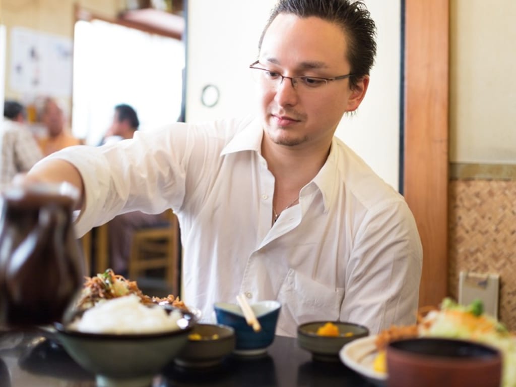男性が定食屋さんで食事しているところ
